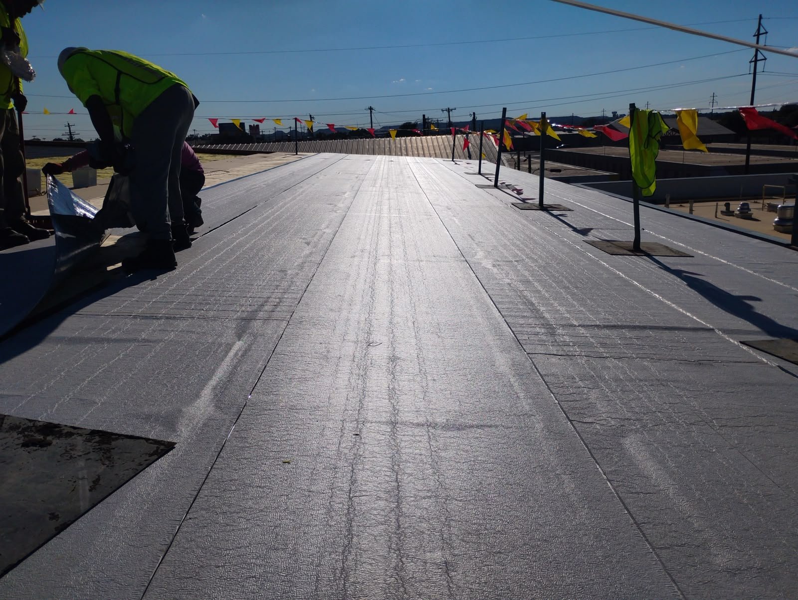 Legendary Construction crew installing membrane roofing on a commercial flat roof